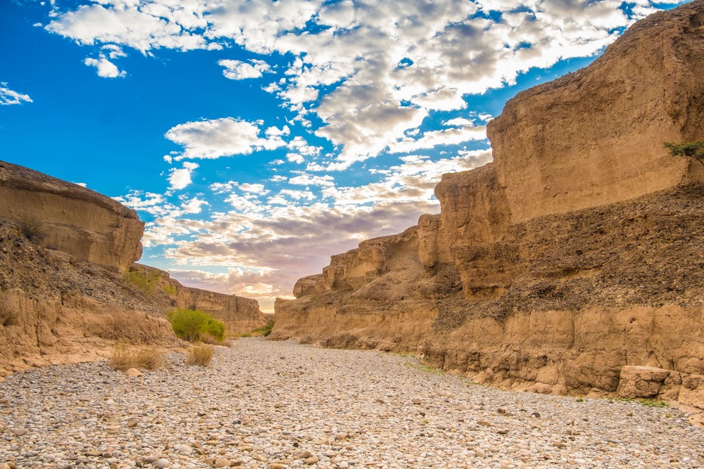 Sesriem Canyon, Sossusvlei, Namib-Naukluft National Park, Namibia. A natural canyon carved by the Tsauchab river in the local sedimentary rock, about a kilometre (0.6 mile) long and up to 30 meters (100 feet) deep. The name Sesriem is Afrikaans and means "six belts",given by settlers on the Dorsland Trek who had to attach together six belts (made of oryx hides) in order to reach buckets down into the canyon to scoop up water. The Sesriem Canyon is only two metres (6.5 feet) wide in some places, and has a portion that permanently contains water, which many animals use.