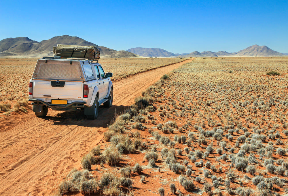 Pickup truck with roof tent is on an adventurous drive through the desert towards the Tiras mountains